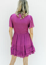 Back view of Model wearing a magenta button up dress with lace and a ruffle hem. 