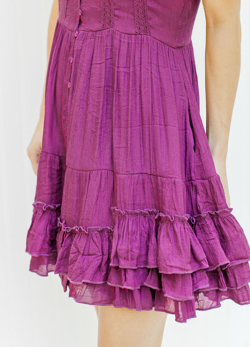 Close up view of ruffle detail on hem of a magenta above the knee dress. 