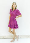 Model wearing a magenta button up dress with lace at the neck and bodice and a ruffle hem. 