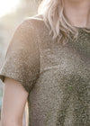 Close up of Blonde model wearing black and gold top.