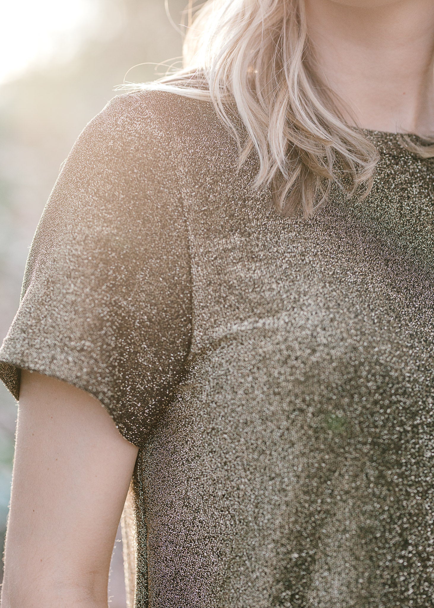 Close up of Blonde model wearing black and gold top.