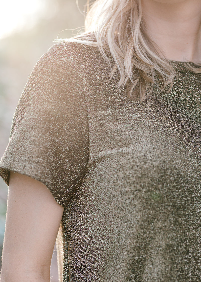 Close up of Blonde model wearing black and gold top.