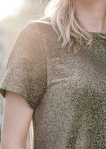 Close up of Blonde model wearing black and gold top.