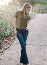 Blonde model wearing black and gold top and jeans.