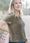 Blonde model wearing black and gold top with short sleeves.