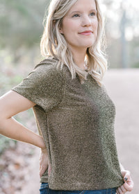 Blonde model wearing black and gold top with short sleeves.