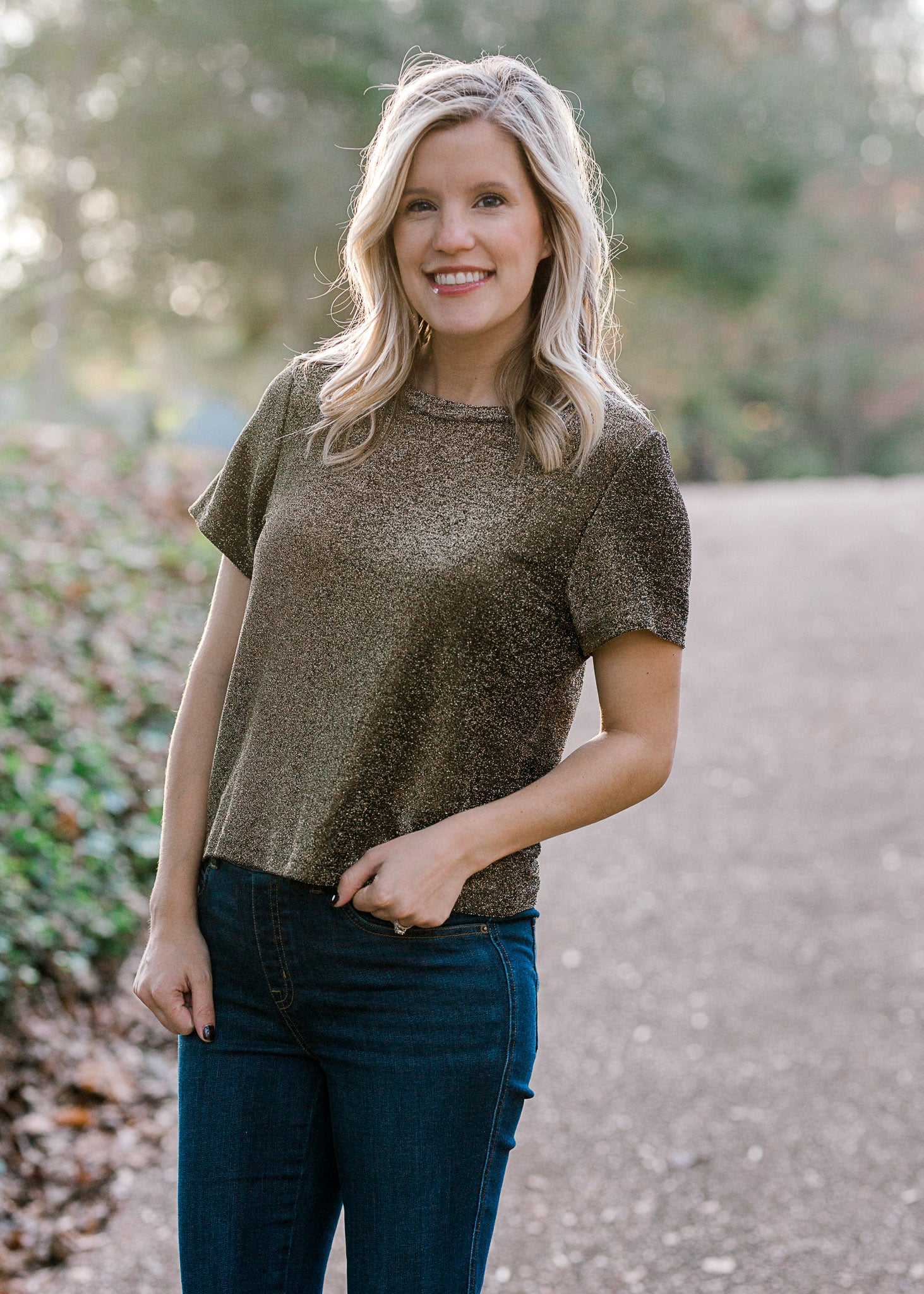Blonde model wearing black and gold top with round neck.