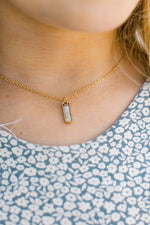 Close up of gold necklace with a pendant with mini on it in gold letters.