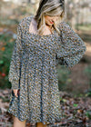 Blonde model wearing a black dress with camel and white floral pattern. 