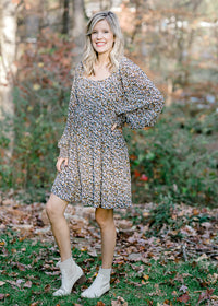 Blonde model wearing a black dress with camel and white floral pattern with booties. 