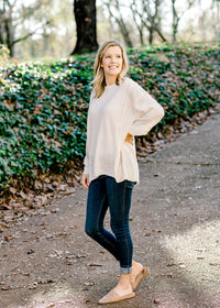 Blonde model wearing an off white sweater. 