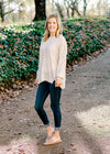 Blonde model wearing an off white sweater with jeans and mules. 