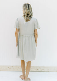 Back view of model wearing a pale mint colored babydoll dress with flutter sleeves. 