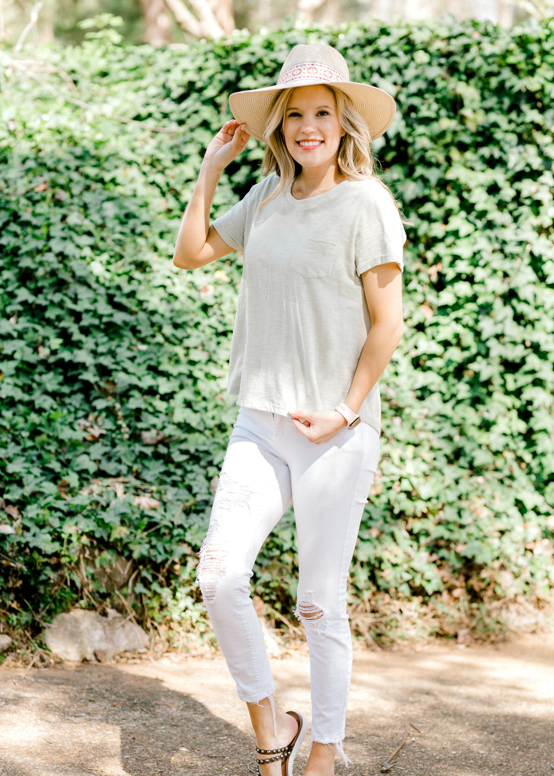 Straw hat with aztec band in cream, red, and green on blonde model with white jeans.