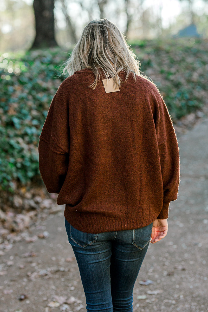 Back view of Blonde model wearing a wine colored sweater.