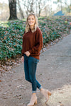 Blonde model wearing a wine colored sweater with jeans and booties. 