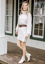 Blonde model wearing ivory sweater dress and belt.