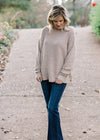 Blonde model wearing ribbed cream sweater with jeans. 