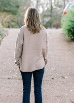 Back view of Blonde model wearing ribbed cream sweater.