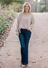 Blonde model wearing ribbed cream sweater with jeans and mules. 