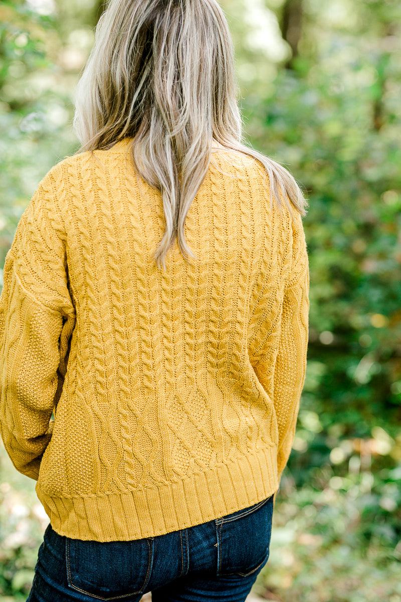 Back view of Blonde model wearing mustard cable knit sweater.