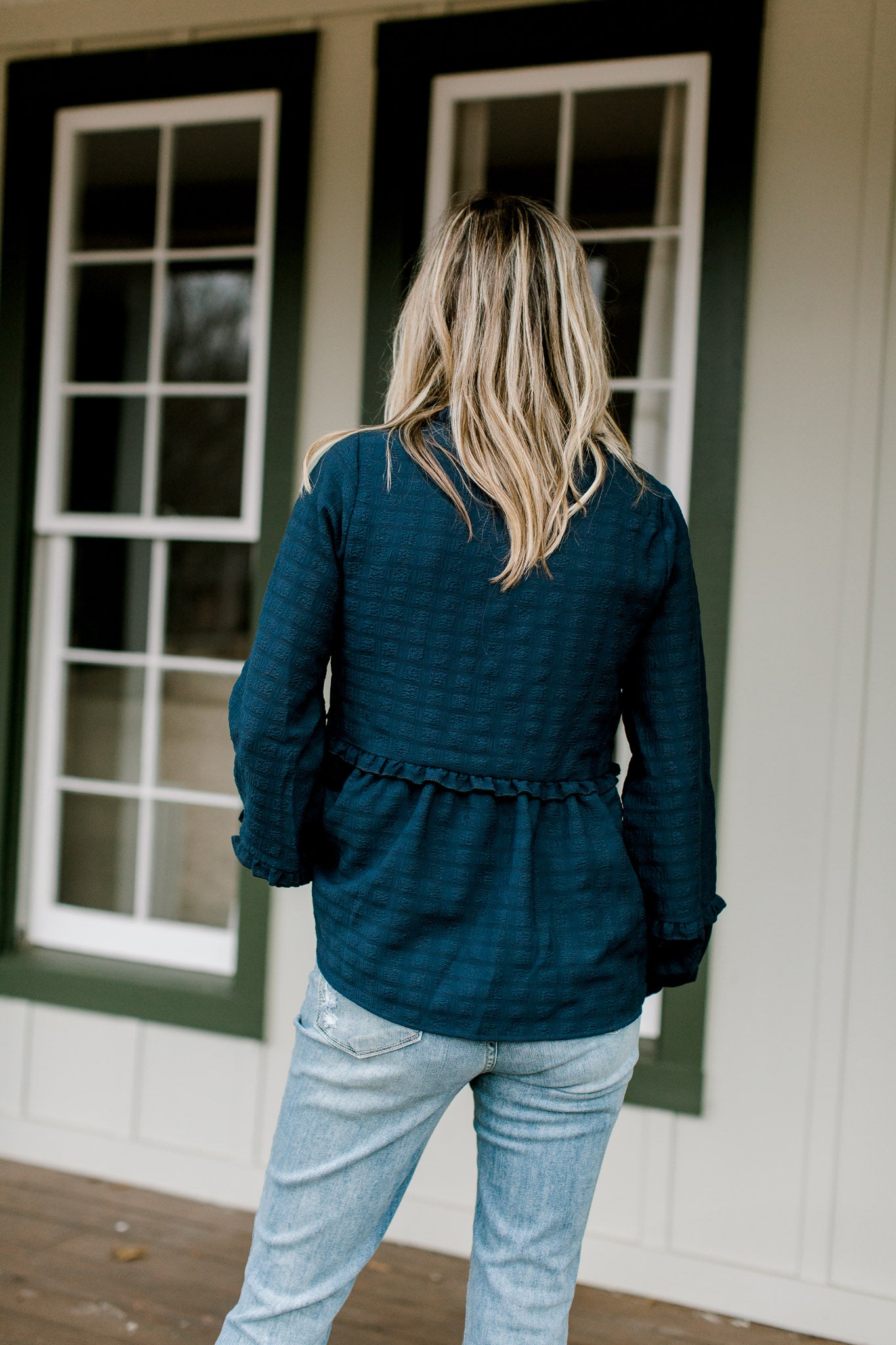 Back view of Blonde model wearing a navy babydoll top.