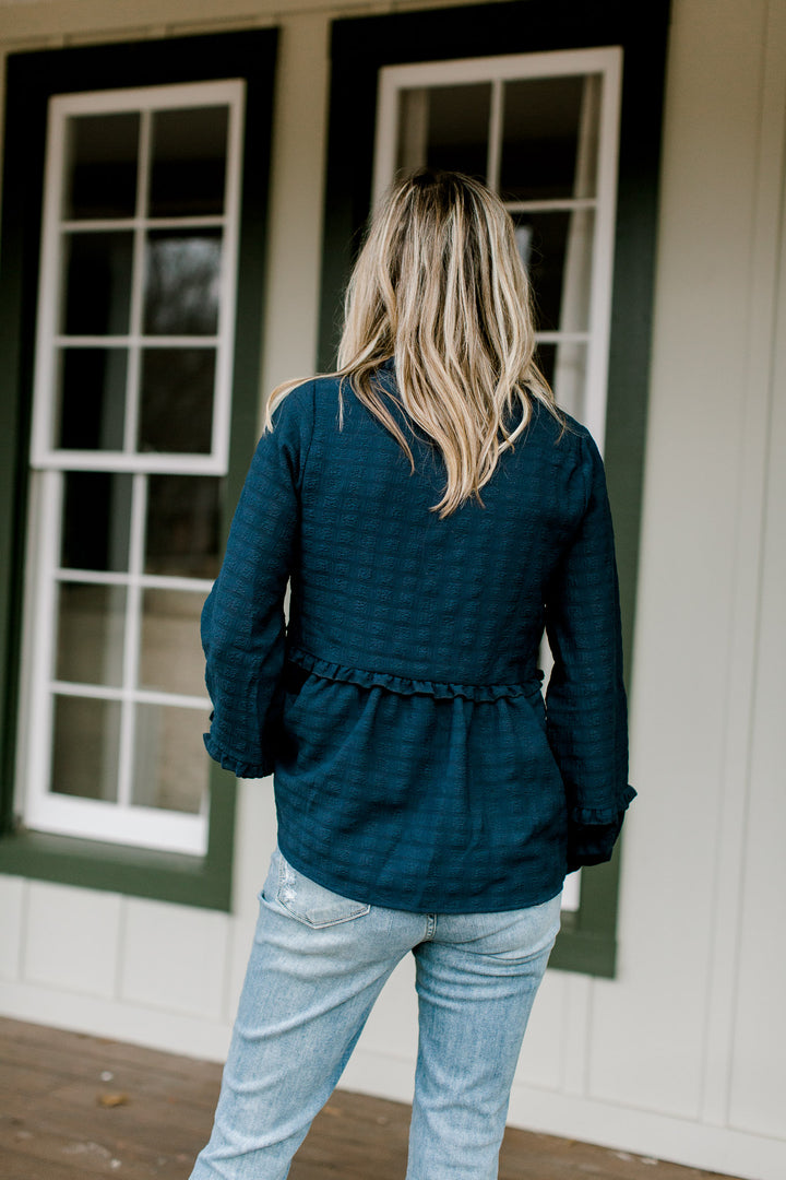 Back view of Blonde model wearing a navy babydoll top.