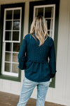 Back view of Blonde model wearing a navy babydoll top.