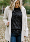 Blonde model wearing black sequin top and jacket.