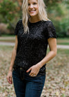 Blonde model wearing short sleeve black sequin jacket.