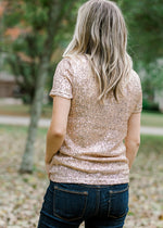 back view of Blonde model wearing rose gold sequin top with short sleeves.