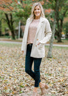Blonde model wearing rose gold sequin top and jacket.