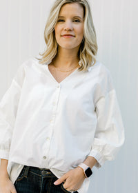 Blonde model wearing a white button up with 3/4 sleeves.