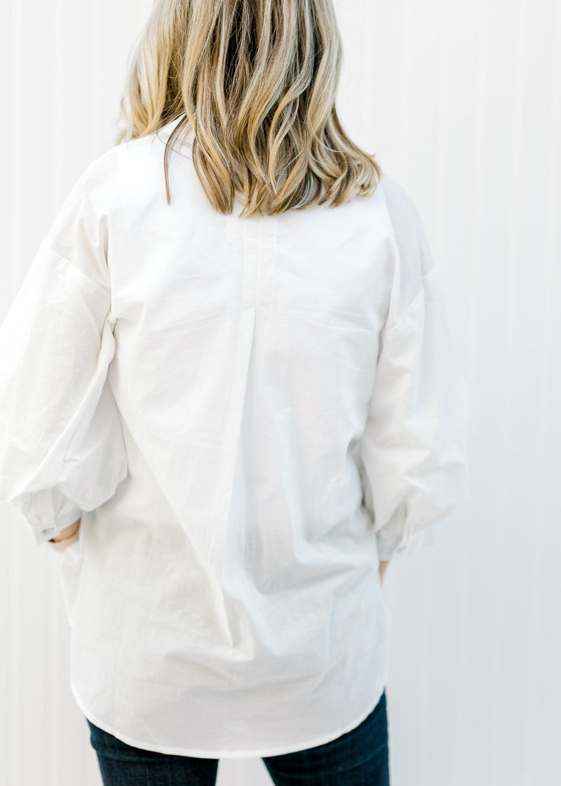 Back view of Blonde model wearing a white button up. 