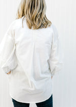 Back view of Blonde model wearing a white button up. 