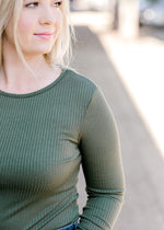 Close up view of Blonde model wearing olive bodysuit.