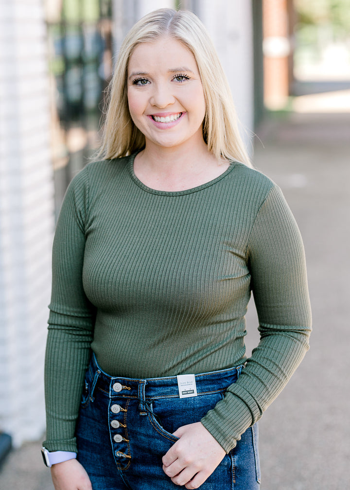 Blonde model wearing olive bodysuit with jeans.