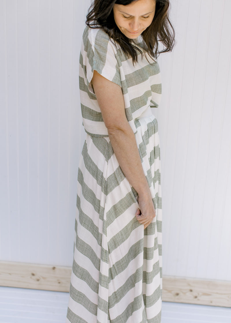 Side view of model wearing an olive and cream striped maxi skirt with a matching crop top. 