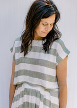 Model wearing a olive and cream striped crop top with short sleeves. 