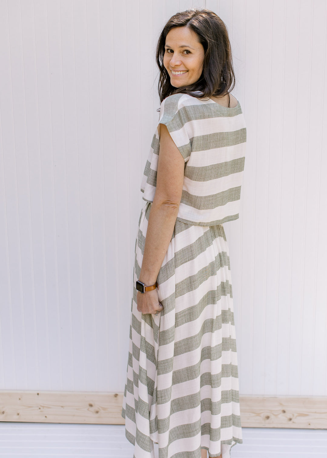 Back view of Model wearing a olive and cream striped crop top with short sleeves.