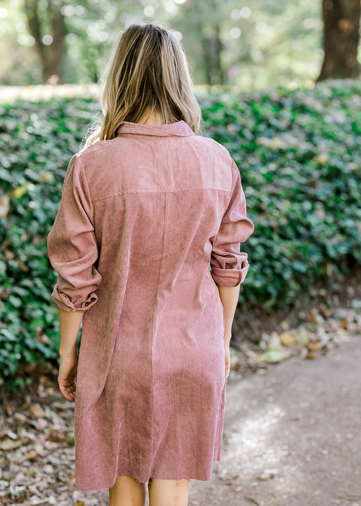 Back view of Blonde model wearing purple button up corduroy dress. 