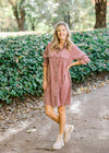 Blonde model wearing purple button up corduroy dress with booties.