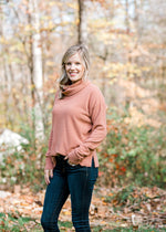 Blonde model wearing a rose colored sweater with jeans. 