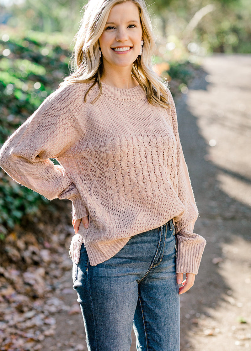Blonde model wearing pearl sweater with cable knit design.