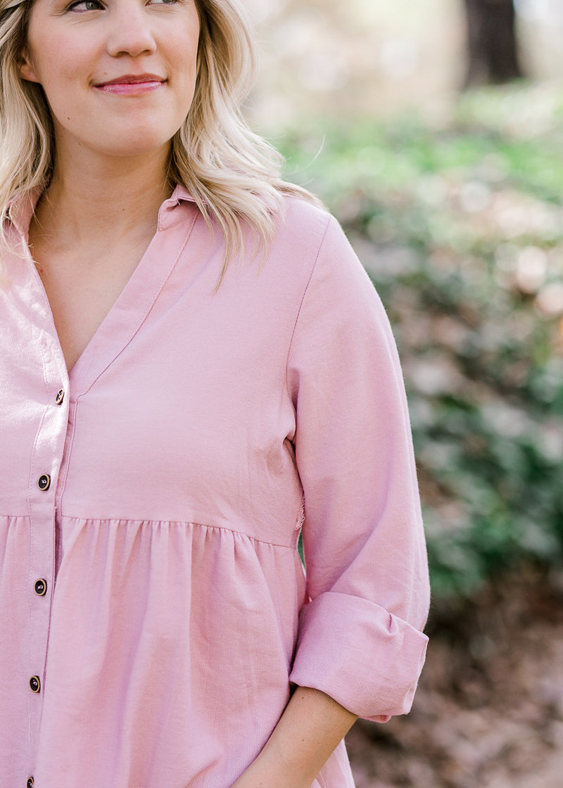 Close up view of Blonde model wearing a pink corduroy button up top.  