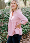 Blonde model wearing a pink corduroy button up top with jeans. 