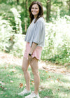Brunette model wearing pink workout short and sneakers.