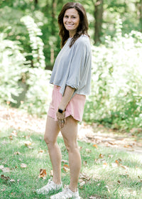 Brunette model wearing pink workout short and sneakers.