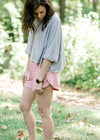 Brunette model wearing pink workout short , loose top and sneakers.