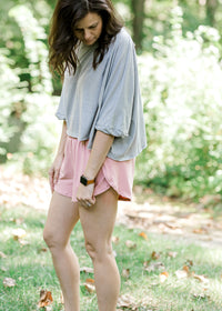 Brunette model wearing pink workout short , loose top and sneakers.